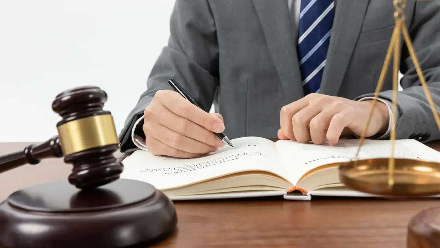 A lawyer signing documents beside a gavel and scales of justice