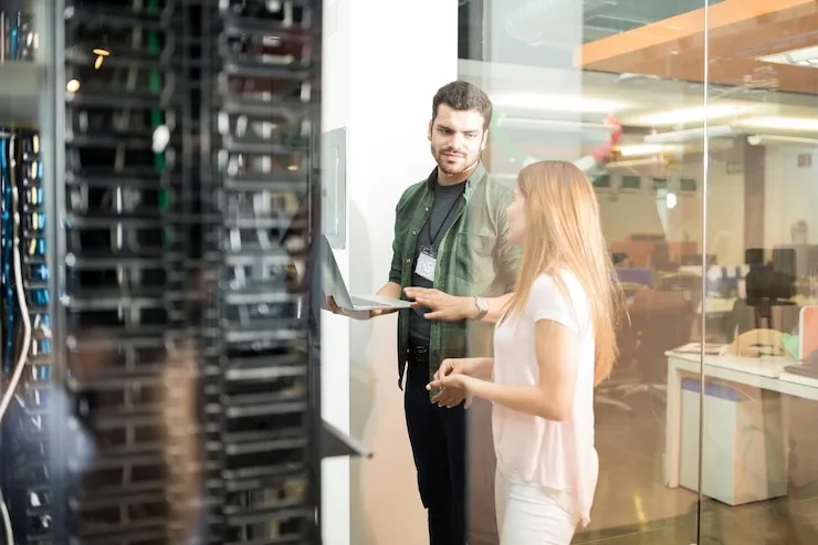 Two engineers talking next to a server rack in an office