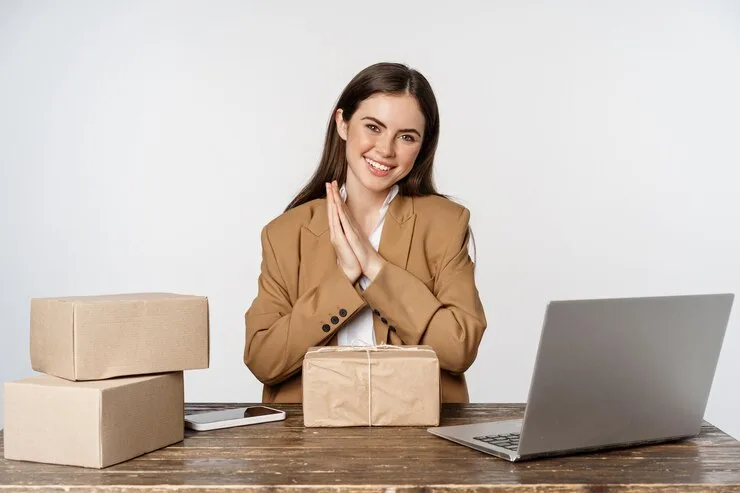 A small business owner at a laptop next to packed orders ready to ship