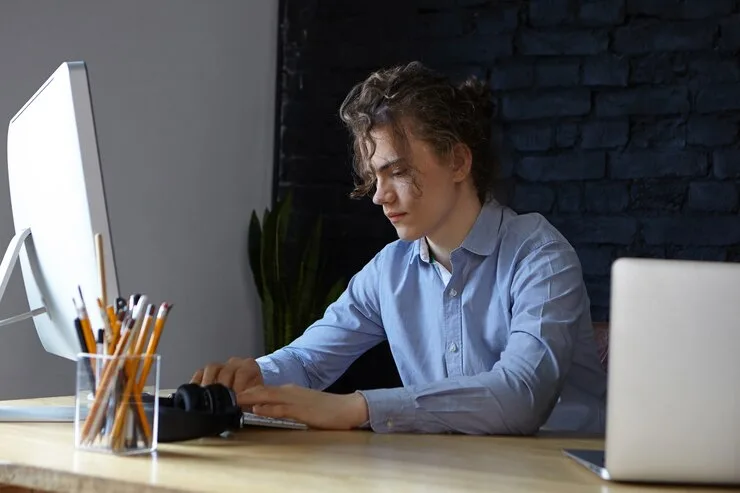 A developer working on a desktop computer and a laptop in a modern office