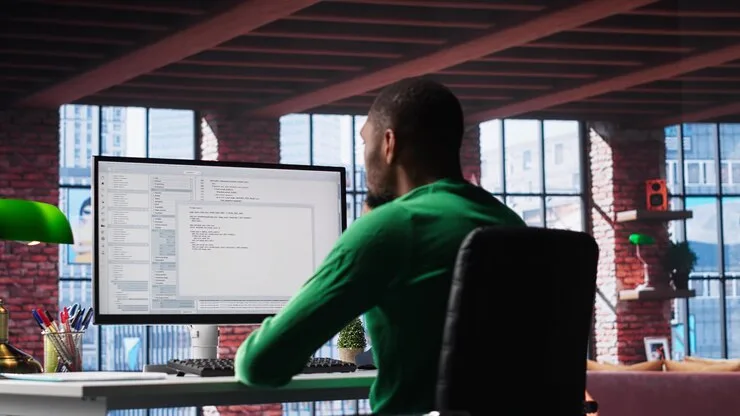 A developer writing code on a large monitor in a loft office