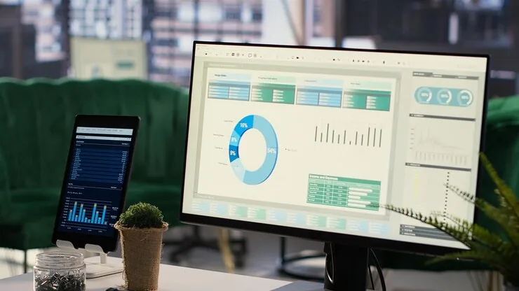 A monitor and tablet showing business reports and charts in an office
